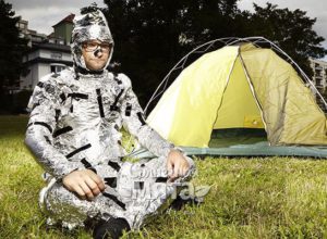 Мужчина в алюминиевой фольге сидит у палатки, фото
