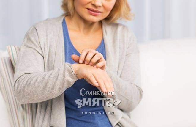 Обеспокоенная женщина смотрит на свои бледные руки, фото