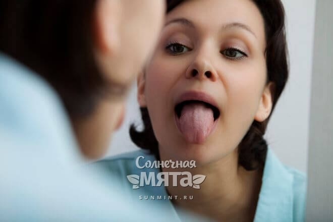 Женщина проверяет свой язык на недостаток витамина B12, фото
