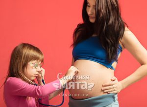 Дочка слушает живот своей беременной мамы, фото