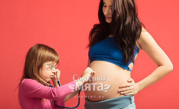 Дочка слушает живот своей беременной мамы, фото