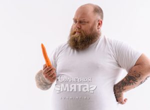 Полный мужчина смотрит на морковку, фото