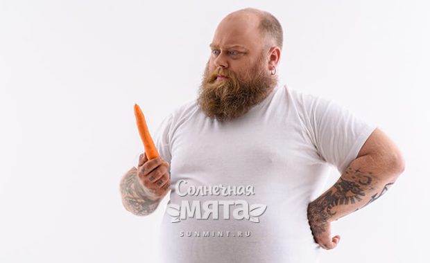 Полный мужчина смотрит на морковку, фото