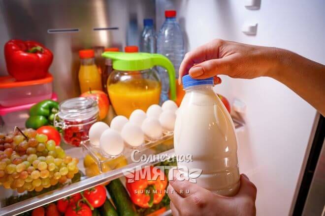 Женщина достает бутылку молока из холодильника, фото