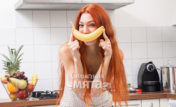 Девушка прикладывает к своему рту банан в форме улыбки, фото
